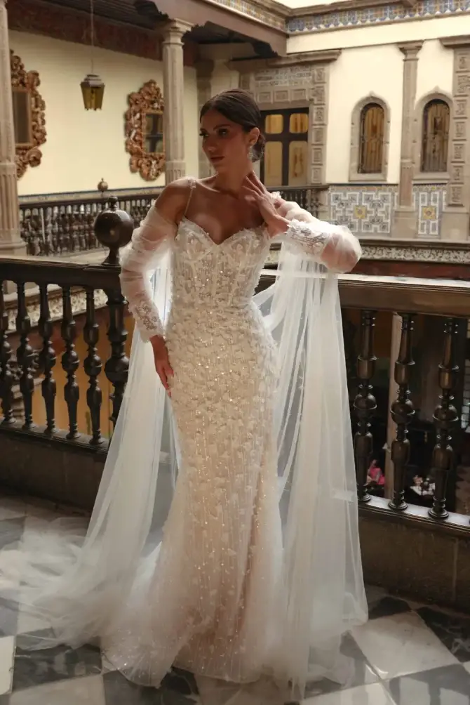 model is wearing a strapless fit and flare wedding dress with a detachable cape
