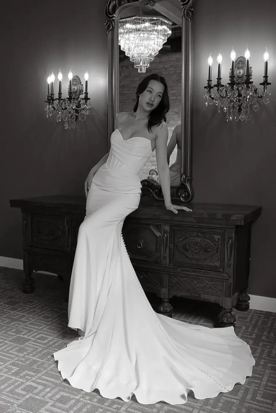 model is wearing a fitted strapless bridal gown with a long train