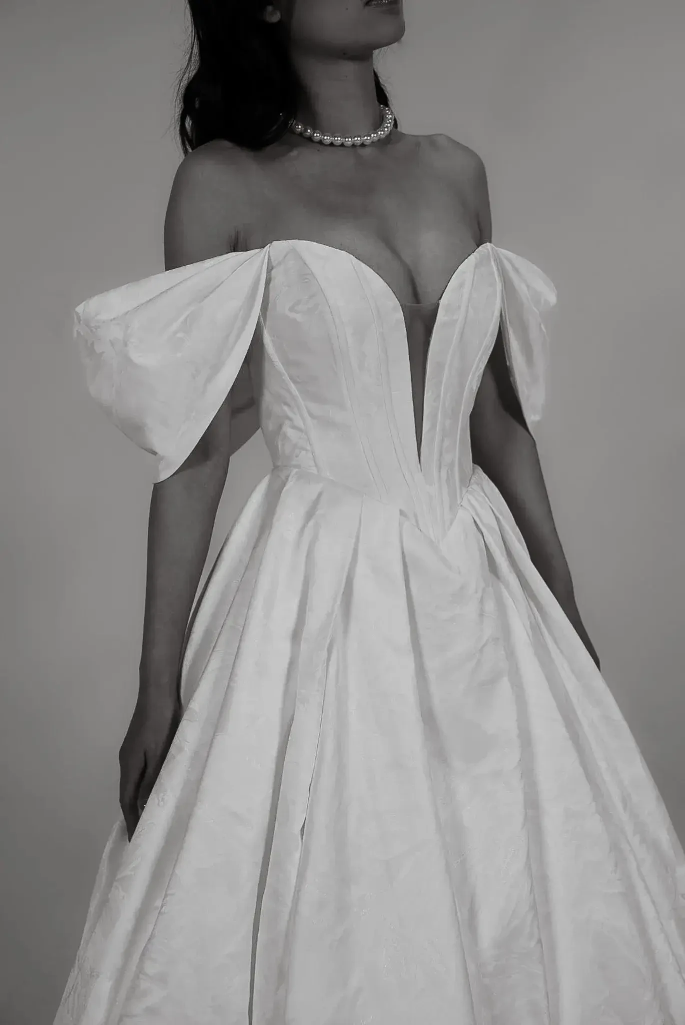 model is wearing an off the shoulder a-line wedding dress with a plunging neckline 