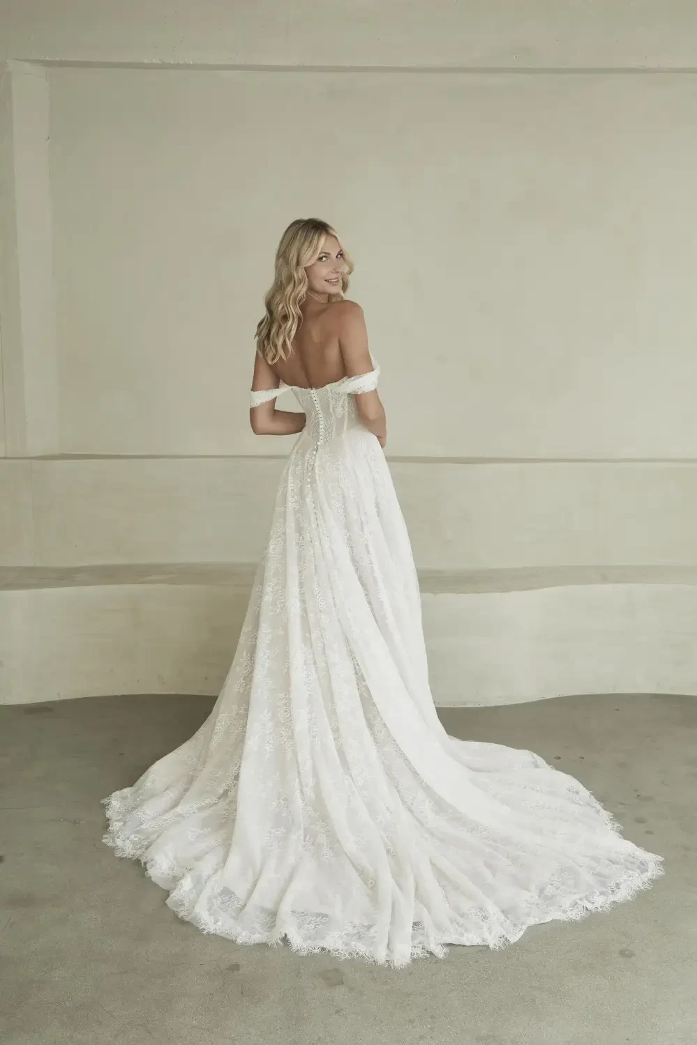 model is wearing a minimalist off the shoulder bridal gown