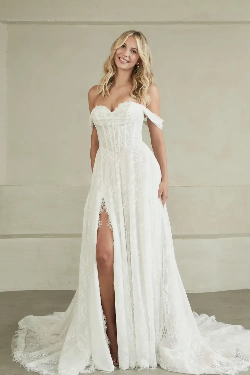 model is wearing a minimalist off the shoulder bridal gown