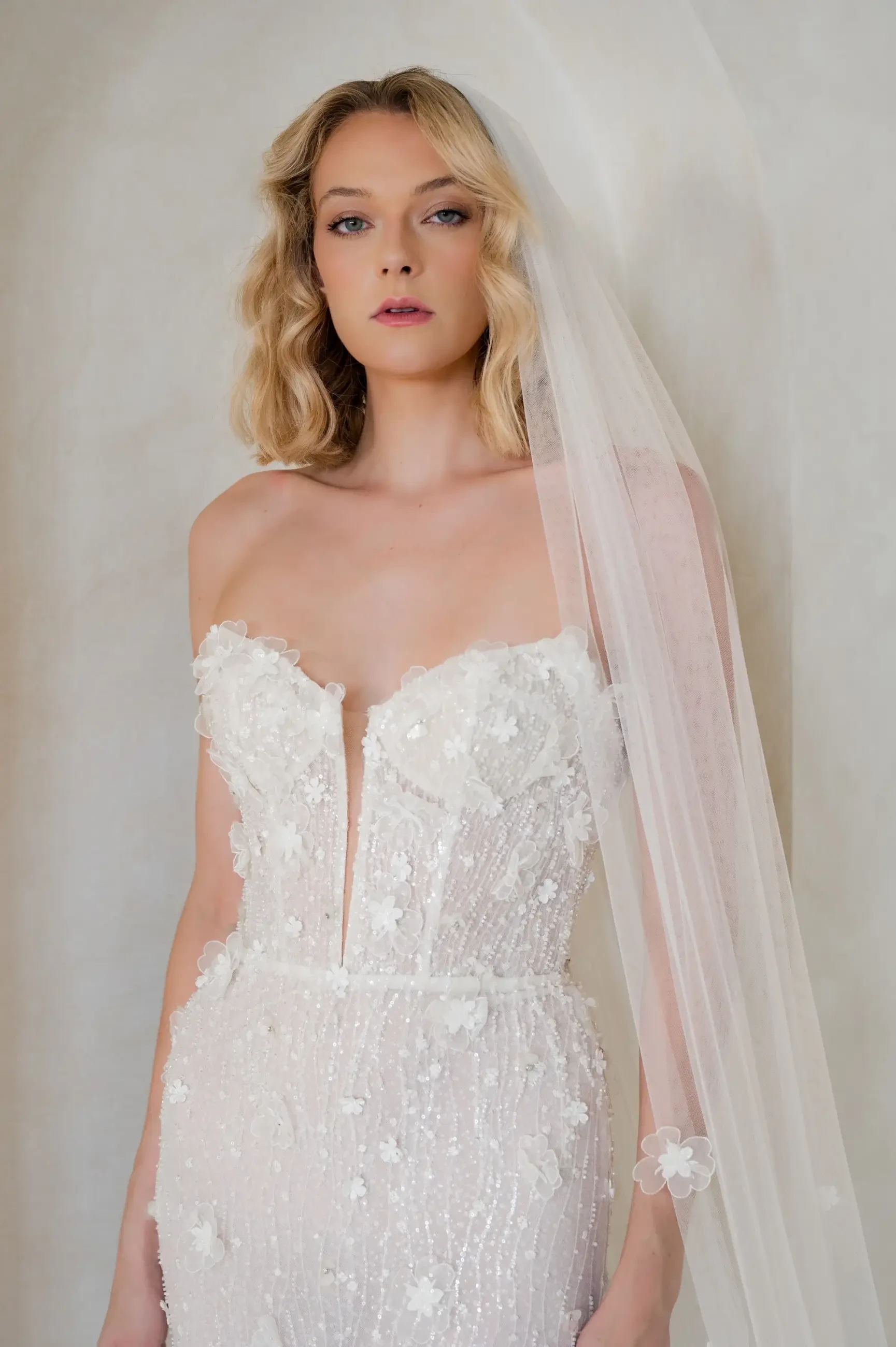 model is wearing a strapless fit and flare wedding dress with a plunging neckline and 3d floral appliques
