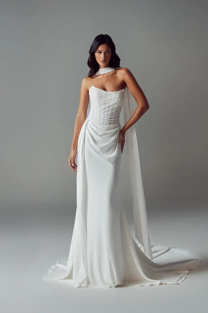 Model wearing a white, strapless gown with a draped cape.